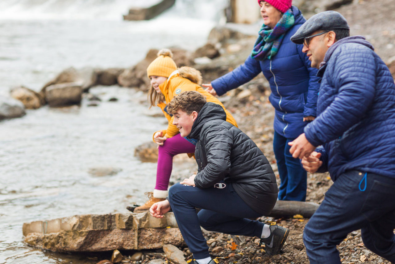 Family of two adults and two children together on coastline