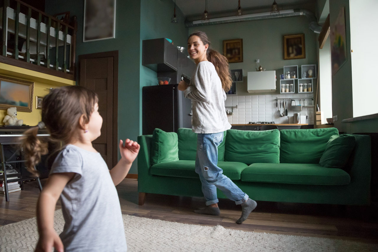 Adult and young girl dancing around together indoors smiling and having fun