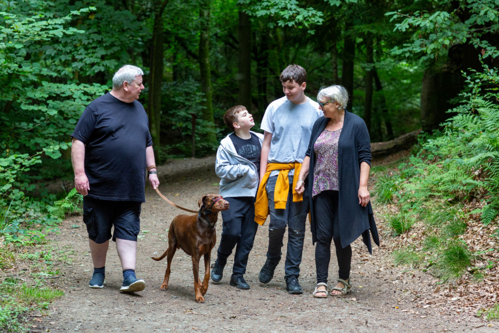 Family walking brown dog in the woods