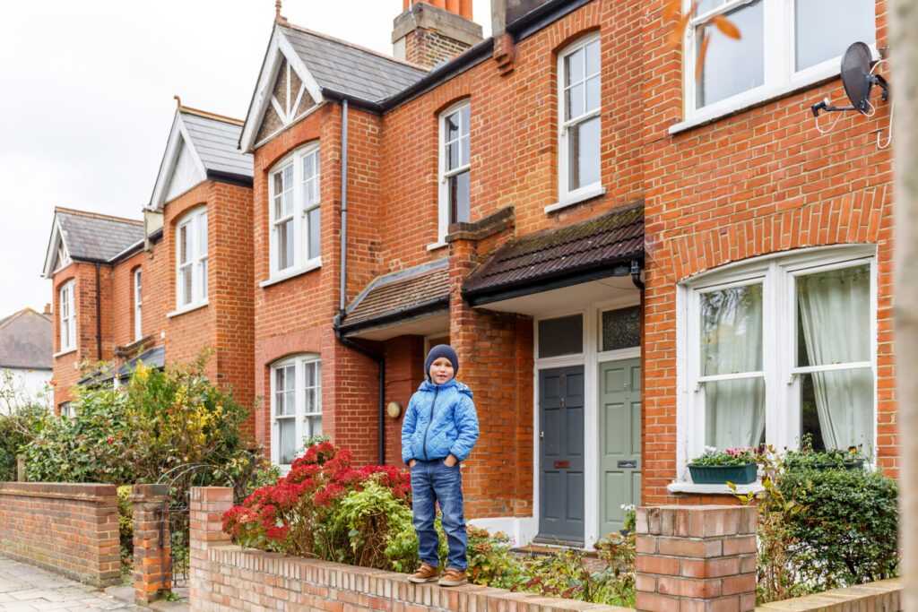 Boy standing on wall outside terraced house