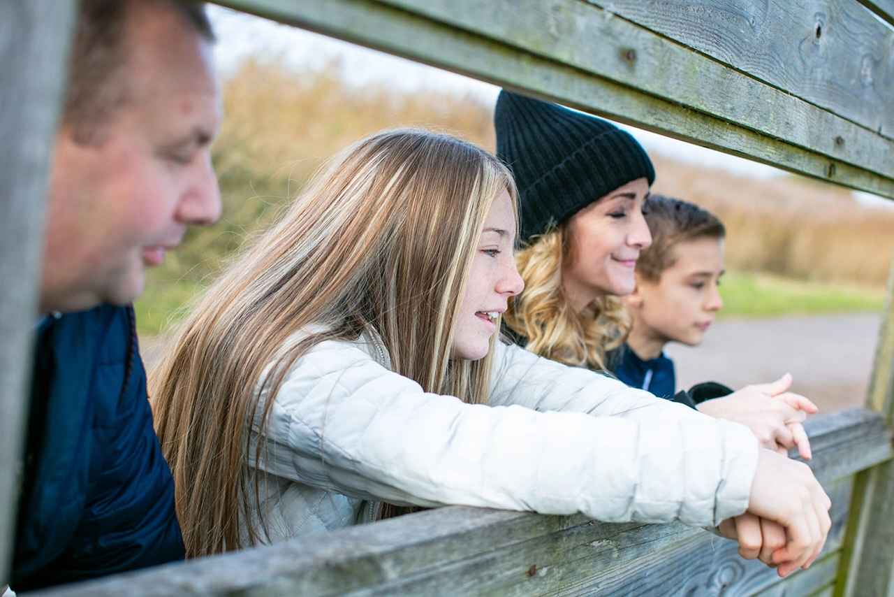 Family of four looking over a wooden fence