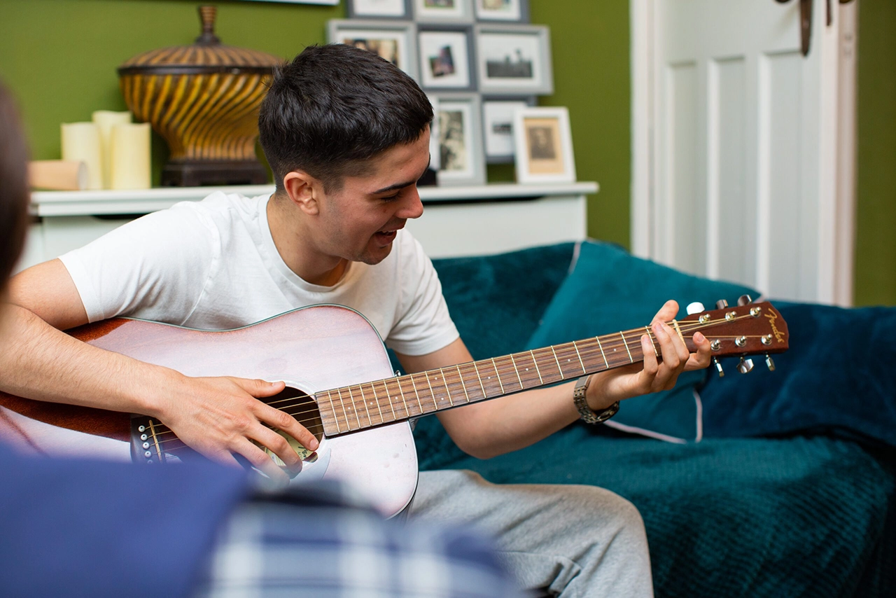 Teenage boy playing guitar at home
