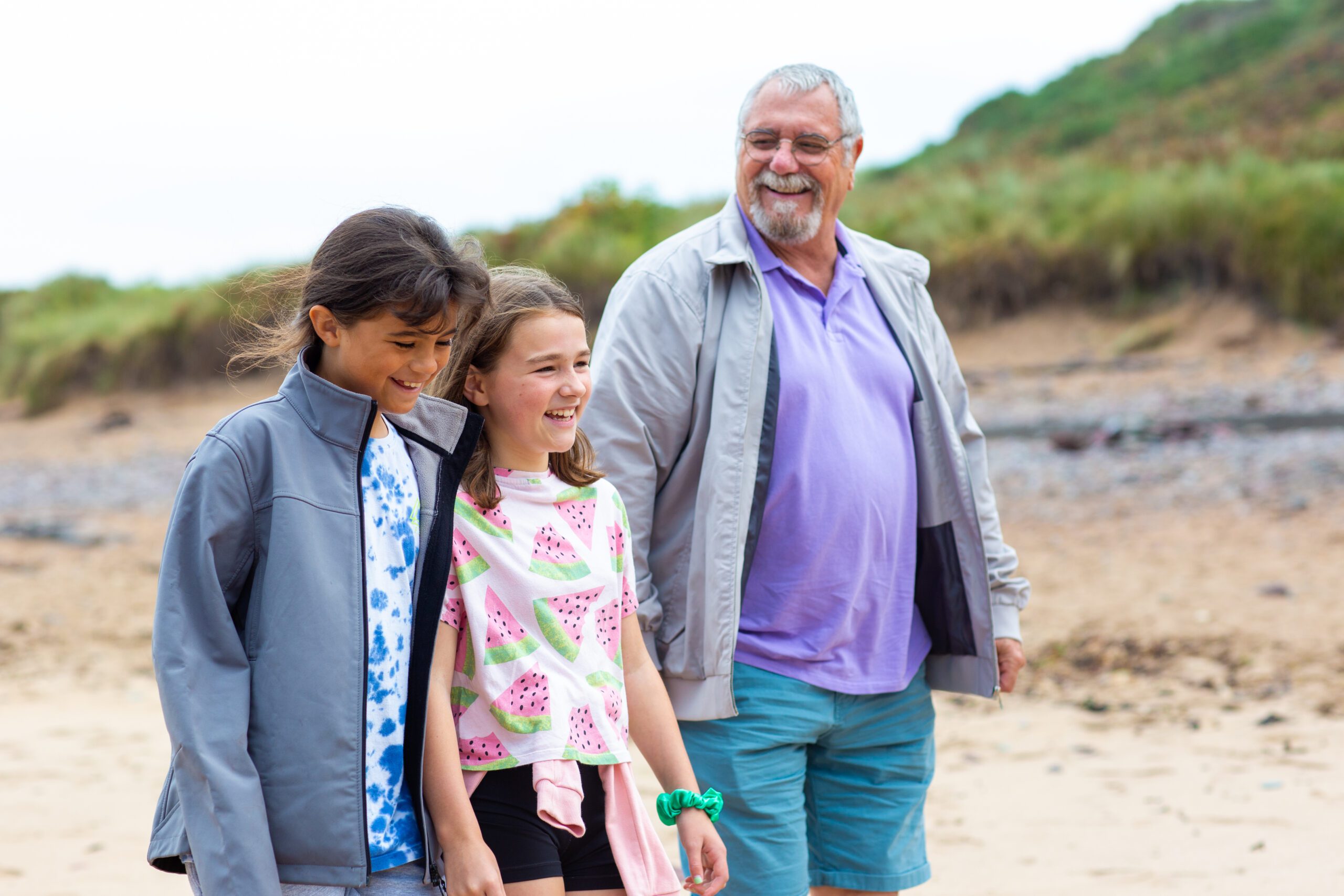 Man and two girls walking on the beach in wales